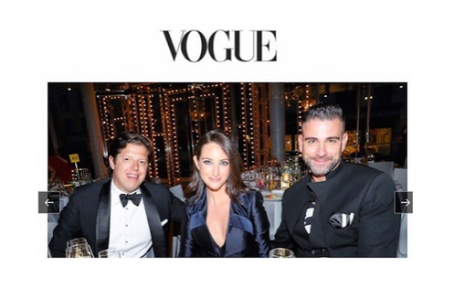 Vogue event photograph of three guests seated at a dinner table.