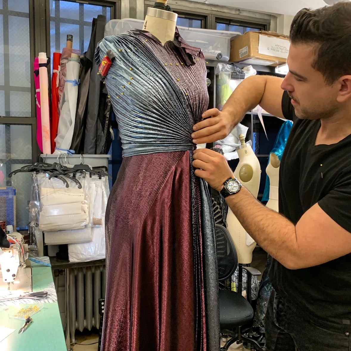 Metallic fabric being hand-draped and pinned in the studio