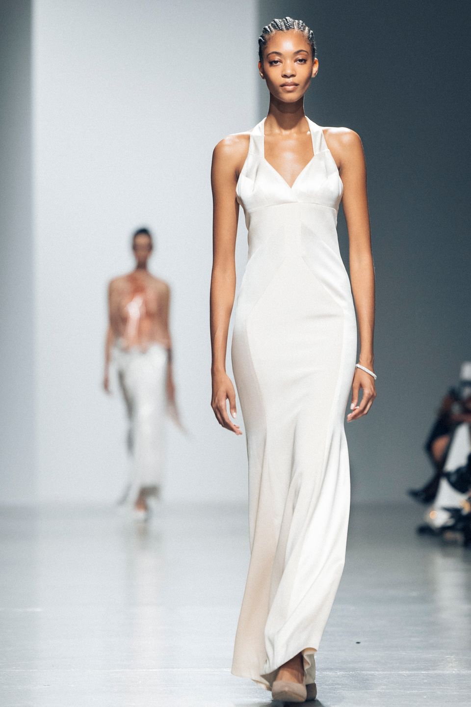 Model in a white flowing gown on the runway